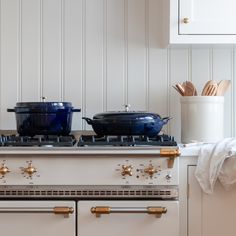 two pots and pans are sitting on the top of an oven in a white kitchen