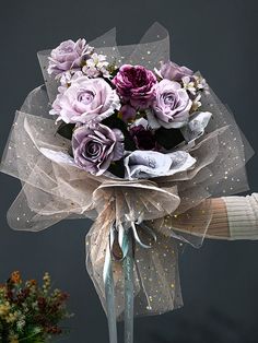 a bouquet of purple roses tied to a metal pole with ribbon around the top and bottom