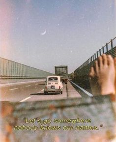 a car driving down a road next to a bridge with a quote written on it