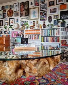 a living room with bookshelves and pictures on the wall behind glass top coffee table