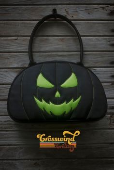 a black and green bag with a pumpkin face on it