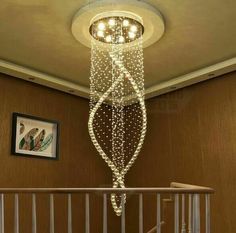 a chandelier hanging from the ceiling in a room with stairs and paintings on the wall