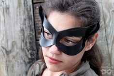 "These classic black leather cat masks are sculpted from tooling leather and painted on both sides. The color is sealed with an acrylic topcoat, and the simple shaping is comfortable and quite flattering on most faces. MEASUREMENTS + MATERIALS ✭ Measures approximately 7\" wide x 4\" high at its highest and widest points. ✭ Ties with gorgeous and durable stretch lace ribbon straps (included). ✭ Hand crafted using tooling leather, dye, paint, sealant, and quality ribbon ties. First photos courtesy Catwoman Cosplay, Superhero Masks, Pointed Ears, Half Mask, Leather Mask, Cat Mask, October 25, Disney Movie, Super Hero Costumes