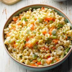 a bowl filled with macaroni salad on top of a wooden table