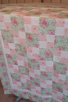 a pink and green checkered table cloth with flowers on it is sitting on the floor