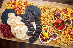 an assortment of cookies, candy and cereals on a wooden platter with mickey mouse ears