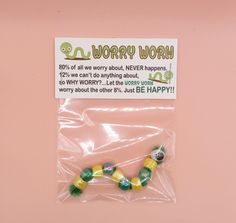 there is a plastic bag with some beads in it on the pink surface and a sign that says worry wormy worm