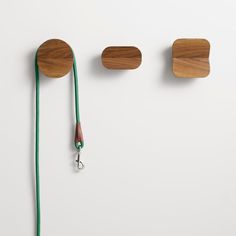 three pieces of wood are hanging on the wall, one is holding a lanyard