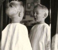 two young boys standing in front of a mirror