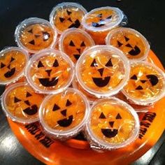 plastic cups with jack - o'- lantern faces on them sitting on an orange plate