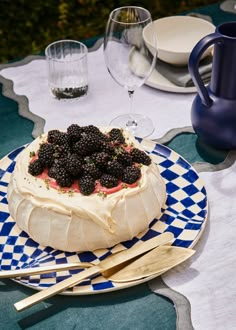 a cake with berries on top is sitting on a blue and white plate next to silverware