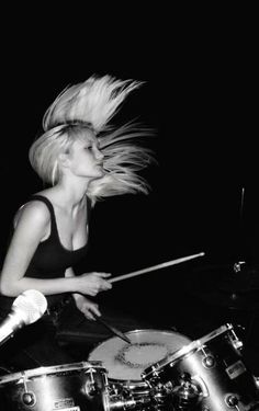 a woman with long hair playing the drums