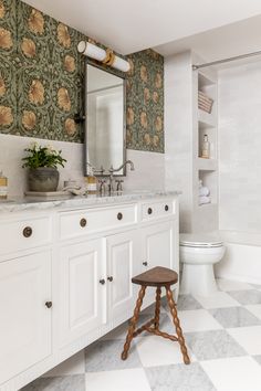 a bathroom with a checkered floor and wallpaper on the walls, along with a wooden stool