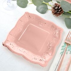 a pink square plate sitting on top of a table next to silverware and flowers