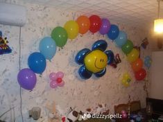 balloons are hanging on the wall in a room with a smiley face balloon decoration above it