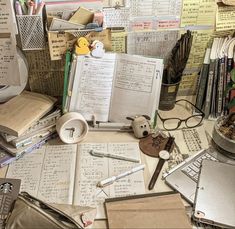 an assortment of papers and pens on a desk with many other items scattered about it