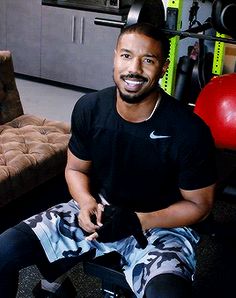 a man sitting on top of a chair next to a red ball and gym equipment