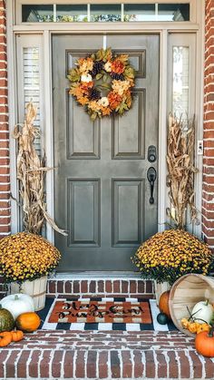 front porch decorated for fall with pumpkins, gourds and cornstatches