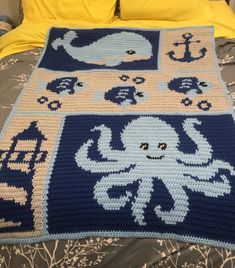 a crocheted blanket with an octopus and whale design on it, sitting on top of a bed