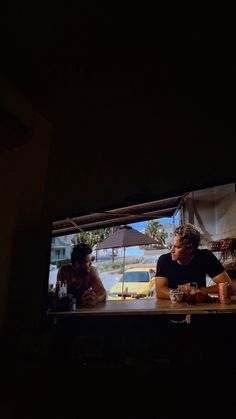 two people sitting at a table in front of a tv