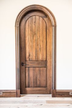 an arched wooden door in a white room