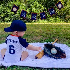 a baby sitting on top of a blanket next to a baseball glove