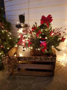 a snowman in a wooden crate with christmas lights around it