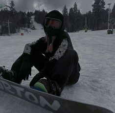 a woman sitting in the snow with her snowboard