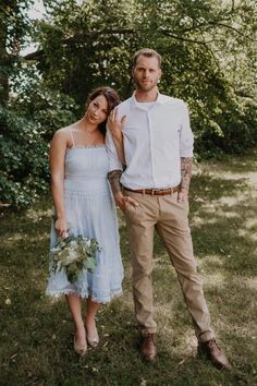 a man and woman standing next to each other in the grass