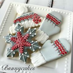 decorated cookies on a white plate with snowflakes and mittens in the middle