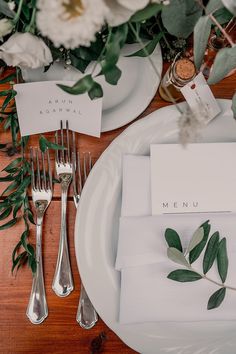 the place setting is set with silverware, napkins and greenery for an elegant touch