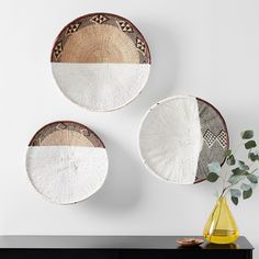 two white and brown plates sitting on top of a black table next to a vase