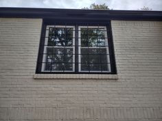 a brick building with two windows and bars on the window sill in front of it