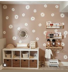 a child's room with pink walls and white flowers on the wall behind it