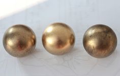 three brass balls are lined up on a white surface