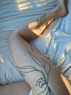 a woman laying in bed with tattoos on her legs