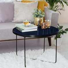 a living room with a couch, coffee table and potted plants on the side