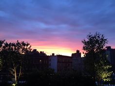 the sun is setting over some buildings and trees