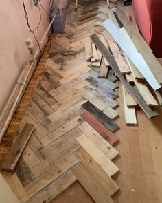 wood flooring being laid out on the floor in front of a red couch and chair