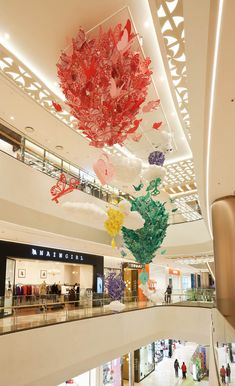 an indoor shopping mall with paper flowers hanging from the ceiling