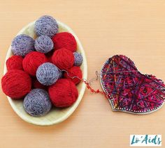 yarn balls in a bowl next to a heart shaped ornament on a table