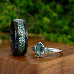 two rings with green and white designs on them sitting on a wooden table in front of some trees