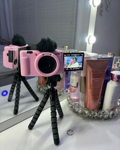 a pink camera sitting on top of a tripod in front of a bathroom mirror