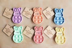 six different colored plastic bunny shaped magnets with tags attached to the back of them