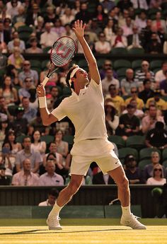 a man holding a tennis racquet on top of a tennis court in front of a crowd