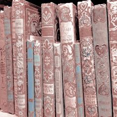 old books are lined up on the shelf in front of each other with ornate designs