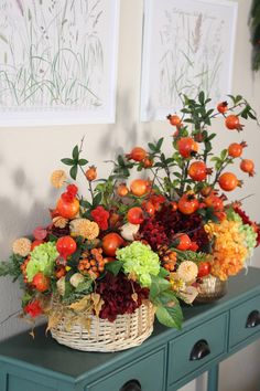 two baskets filled with flowers sitting on top of a green table next to pictures and plants