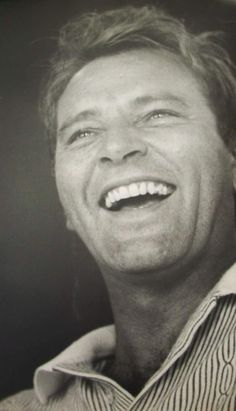 a black and white photo of a man smiling with his teeth wide open in front of him