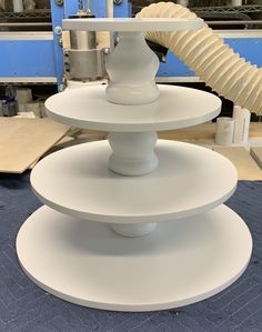 three tiered white vases sitting on top of each other in front of a machine