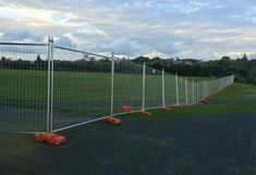 several orange cones sitting on the side of a road next to a fenced in field